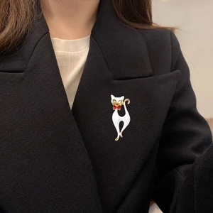 Élégante broche chat blanc avec nœud rouge sur revers de costume noir, détails dorés