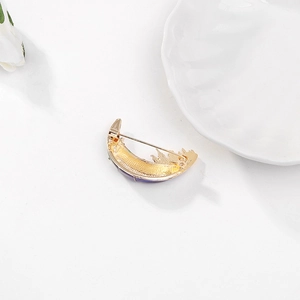 Golden crescent moon brooch with purple and green enamel detail on pure white background