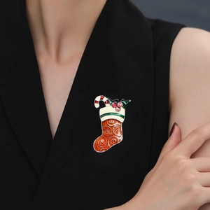 Detailed view of a festive red Christmas stocking brooch with enamel finish on a suit
