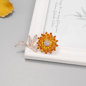 Détail de la broche tournesol en strass avec cristaux orange sur un cadre en or rose