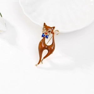 Vue détaillée d'une broche chat vintage avec émail marron et nœud bleu sur décor blanc