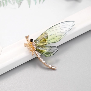 Detail of dragonfly brooch with gold metal frame, white rhinestones and gradient wings