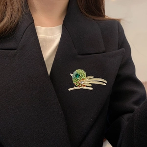 Vue détaillée d'une broche hibou avec strass colorés sur le revers d'un blazer noir