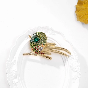 Détail macro d'une broche oiseau en émail vert avec une pierre en forme de goutte