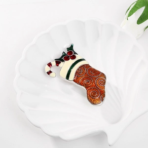 Detail of Christmas stocking brooch with enamel finish on a white ceramic shell tray