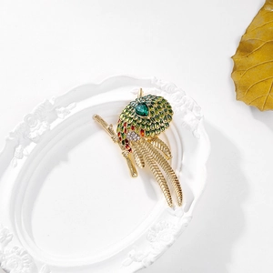 Broche perroquet en émail vert avec cristaux sur branche dorée et assiette blanche