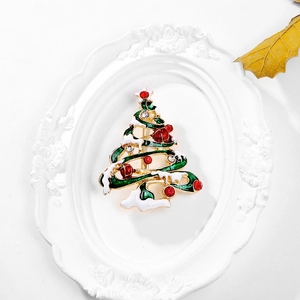 Gros plan d'une broche sapin de Noël scintillante avec émail vert et strass rouges festifs