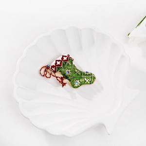 Christmas stocking brooch with red and green enamel and crystal accents on a tray