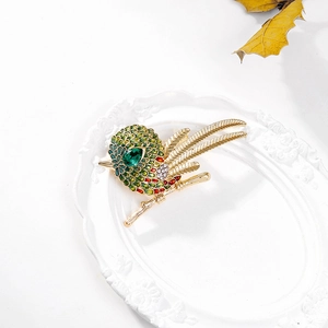 Exquise broche oiseau avec plumes en émail coloré et gemme verte sur un plateau blanc