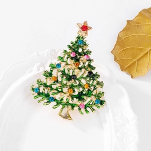Detail einer Weihnachtsbaum-Brosche mit grünem Emaille und bunten Strasssteinen auf Rahmen