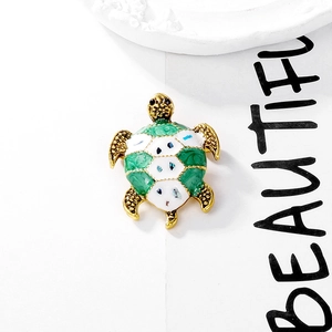 Detail of vintage sea turtle brooch with green enamel shell and golden metallic texture
