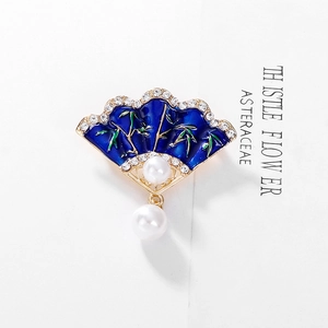 Macro detail of a fan-shaped Chinese brooch with blue enamel, bamboo motifs and pearls