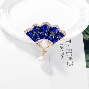Detail of a vintage Chinese fan brooch with blue enamel bamboo and pearl pendant