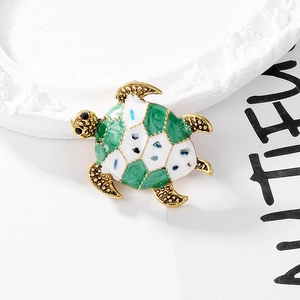Macro shot of green and white enamel sea turtle brooch with gold metal details