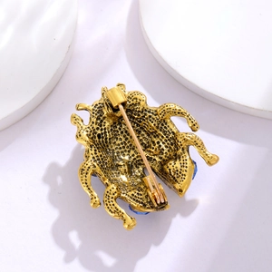 Golden ladybug beetle brooch with honeycomb texture and blue gemstone accents