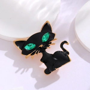 Dettaglio della spilla a gatto nero con occhi in gemma verde e finiture dorate eleganti