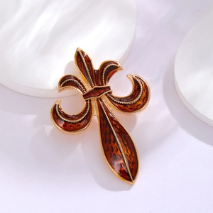 Macro shot of fleur-de-lis brooch with amber enamel and gold metal detailing
