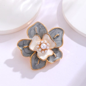 Macro shot of camellia brooch with grey enamel petals and center pearl detail