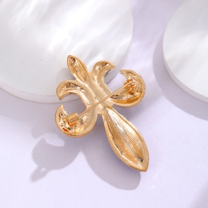 Golden fleur-de-lis brooch back view with secure rotating pin on a white stand