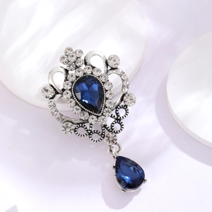 Macro detail of Baroque silver brooch with deep blue pear-cut gems and sparkling rhinestones
