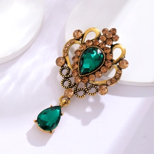 Macro detail of Baroque vintage brooch with green crystals and antique gold filigree
