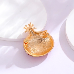 Back view of gold plated pomegranate brooch with safety pin fastener on white base