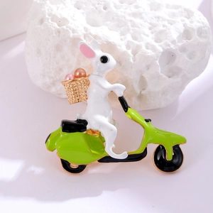 Detailed close-up of a cartoon bunny on a green scooter brooch with pearl accents
