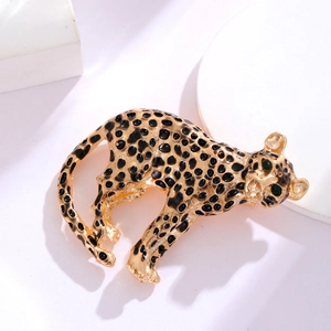 Détail macro de la broche léopard dorée vintage avec yeux en gemmes vertes et taches en émail