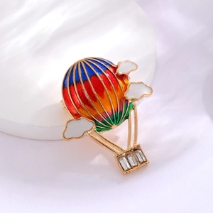 Colorful hot air balloon brooch with sparkling rhinestones and clouds on white stone base