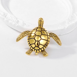 Detailed view of turtle brooch shell with antique gold finish on white plaster tray