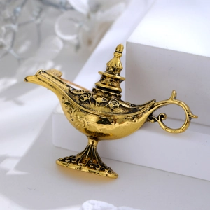 Detailed macro view of an exotic Aladdin lamp brooch in antique gold finish and relief pattern