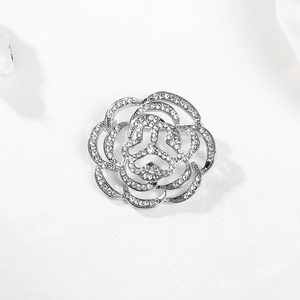 Détail macro d'une broche camélia en argent ornée de cristaux et pétales étagés