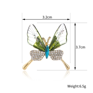 Elegant butterfly brooch with translucent green wings and blue gemstone inlay