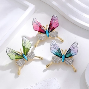 Three gradient acrylic butterfly brooches with rhinestones and gold plating on white decor