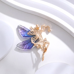 Exquisite goldene Engelsflügel-Brosche mit lila Schmetterlingsflügeln auf weißem Grund