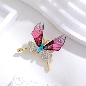 Macro detail of acrylic butterfly brooch with pink gradient wings and rhinestone inlay