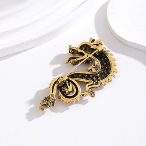 Back view of vintage gold dragon brooch with intricate metalwork on minimalist podium