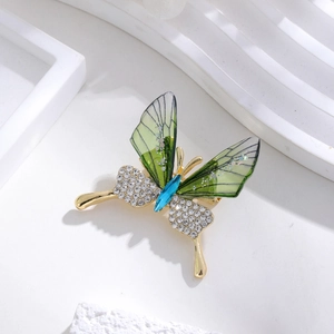 Detail of butterfly brooch featuring green acrylic wings and sparkling white crystals
