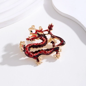 Macro de la broche dragon dorée avec écailles en émail rouge sur fond blanc pur