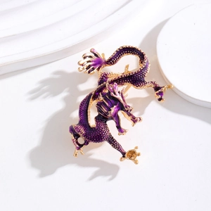 Détail d'une broche dragon en émail violet avec bords dorés sur un support blanc