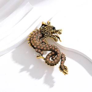 Close-up of vintage dragon brooch with brown rhinestones on a white textured background