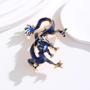 Détail d'une broche dragon en émail bleu avec écailles dorées sur un support blanc