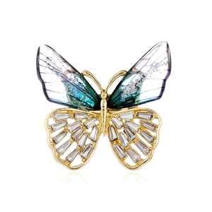 Élégante broche papillon avec ailes dégradées bleues et strass sur monture dorée