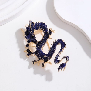 Gros plan d'une broche dragon en émail bleu avec bordure dorée sur socle blanc