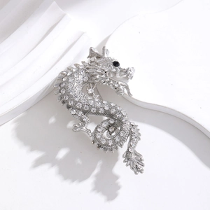 Detailed view of Chinese dragon brooch with silver metal finish and sparkling rhinestones
