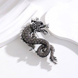 Detailed close-up of retro silver dragon brooch with exquisite grey rhinestones and black gem eyes