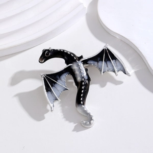 Macro detail of a black and white enamel dragon brooch with polished silver edges