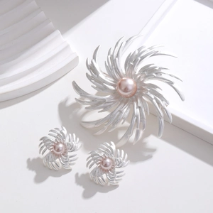 Close-up of vintage silver floral brooch and earrings set with central pink pearls