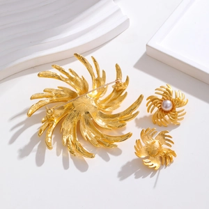 Detailed macro view of vintage gold floral brooch and earrings with pearl accents
