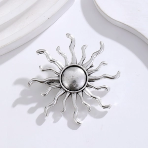 Macro shot of sunburst vintage brooch with antique silver finish on a white geometric base